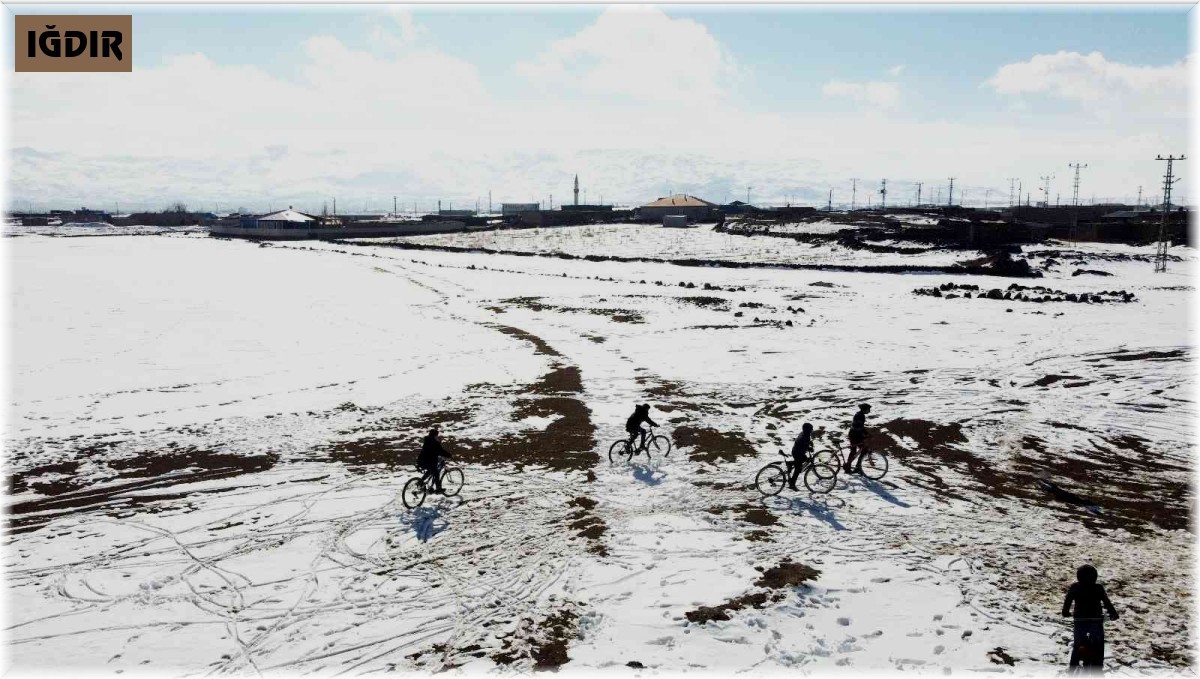 Çocuklar kar üzerinde bisiklet sürüp balon uçurdular