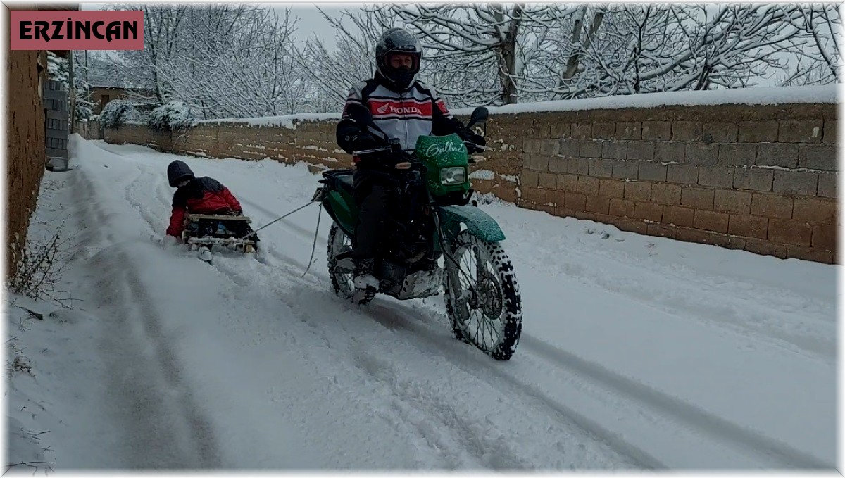 Motosiklete bağladığı kızaklarla çocukları karda eğlendirdi