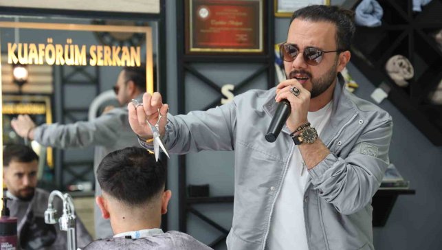 Bir elinde makas diğer elinde mikrofon