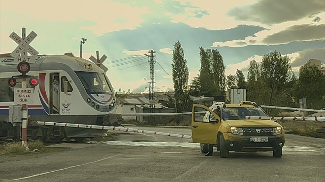 Bariyerlerin kapanmasıyla hemzemin geçitte kalan taksi, trenle çarpışmaktan "kıl payı" kurtuldu