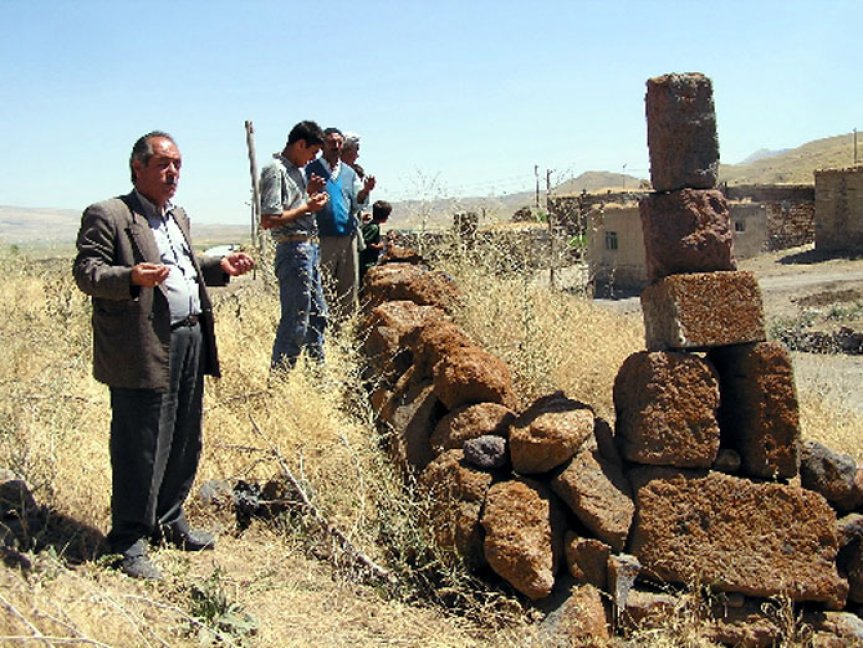 Ağrı Patnos Taşkın köyünde Tokatlı Şeyh Ahmet'e ait olduğu söylenen uzun taş mezarın yanında duran kişiler.