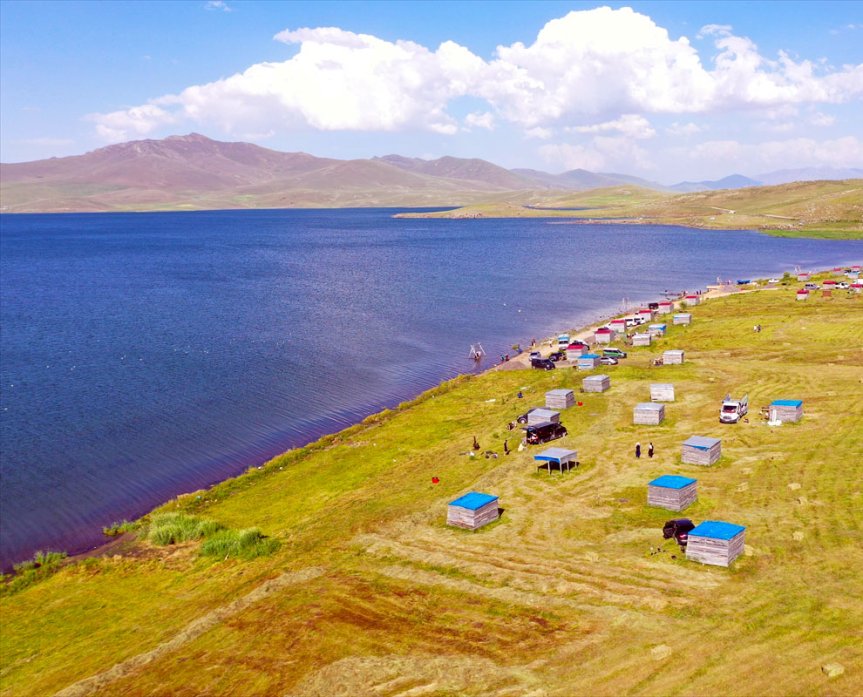 Ziyaretçiler, Balık Gölü kıyısındaki tesislerde serin havanın ve geniş dağ manzarasının keyfini çıkarıyor.