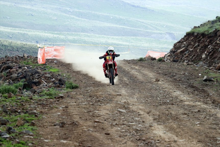 Enduro sporcusu, dağ yolunda toz bulutu içinde ilerledi.