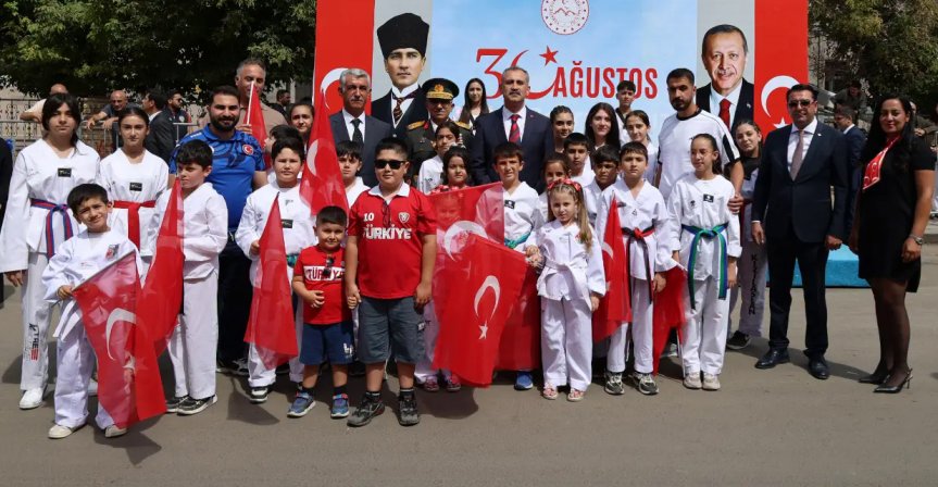 Zafer Bayramı etkinliklerine katılan çocuklar ve sporcular, Türk bayraklarıyla tören sonunda hatıra fotoğrafı çektirdi.