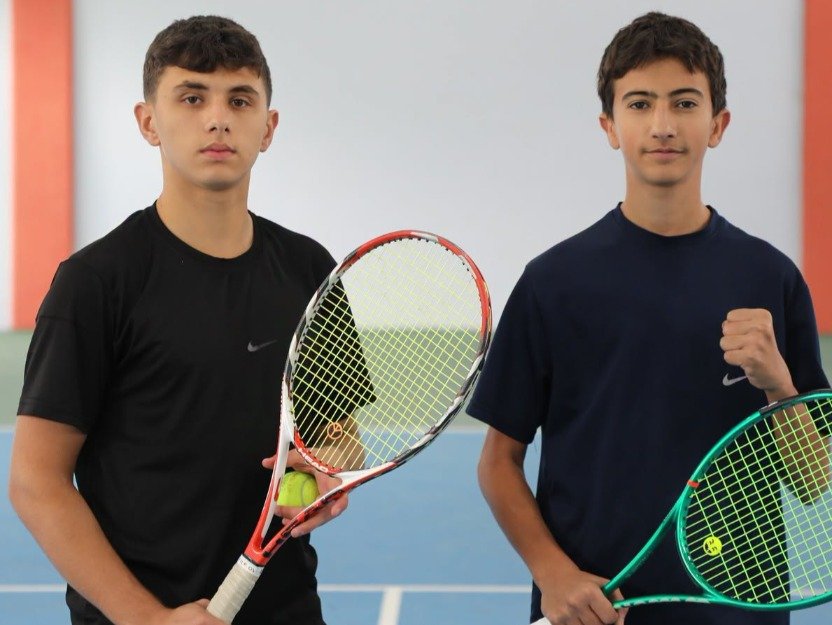 Ağrı'daki Türkiye Tenis Ligi turnuvasında raketleriyle kortta poz veren iki genç tenisçi