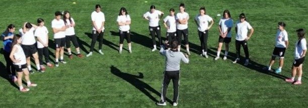 Ağrı Kadın Futbol Takımı futbolcuları, sahada teknik sorumlunun etrafında toplanarak talimatları dinliyor.