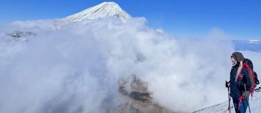 Küçük Ağrı Dağı'ndaki bir dağcı, bulut denizinin üzerinde yükselen Büyük Ağrı Dağı'nın karlı zirvesini izliyor.